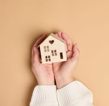 Wooden miniature model house on a brown background. Real estate insurance concept, environmental protection, family happiness