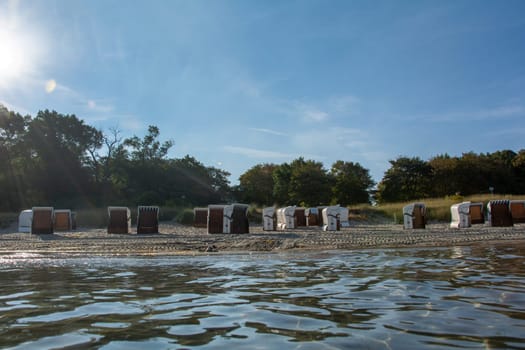 View of beach chairs on the sandy beach from the water of the Baltic Sea, with sun,on Poel, Germany