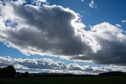 Dark clouds are gathering with blue sky and green landscape