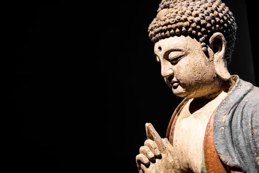 Buddha Statue - Concept of Zen, Spirituality, Peace. Copy space on Black Background, texture light
