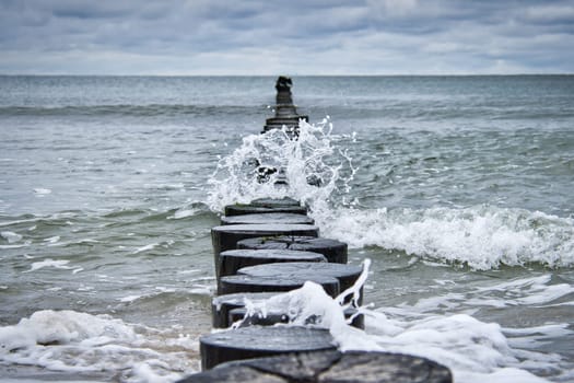 Groynes jut out into the Baltic Sea. Wooden trunks to protect the coast. Landscape from the sea