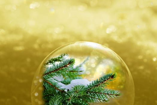 Christmas golden background with glittering snowflakes and fir branches in a ball
