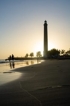 Lighthouse in Maspalomas ( Faro de Maspalomas ) on the Canary Island of Gran Canaria in Spain at sunset with sandy beach and sea