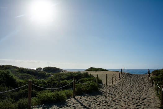 A footpath through the sand dunes to the sea, Maspalomas on Gran Canaria in Spain. With blue sky on a sunny day.