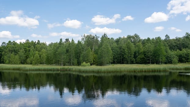 Reservoir at the red moor in the high Rhoen, Hesse, Germany. With blue sky and white clouds and reflection in the water