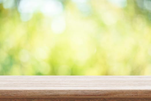 Empty wooden table and green bokeh nature background. Outdoor mockup for food product display montage. Summer garden blur backdrop and rustic desk placement.