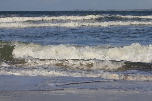 Waves with white crests inundate the sandy beach