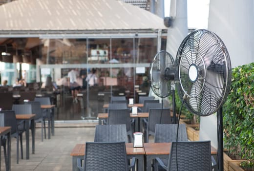 Water Vapour Mist Fan splashing vaporized water at terrace restaurant. Hospitality sector at summer