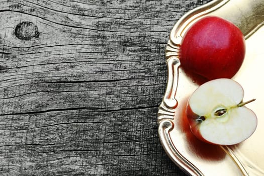 An apple on a golden plate on a wooden table