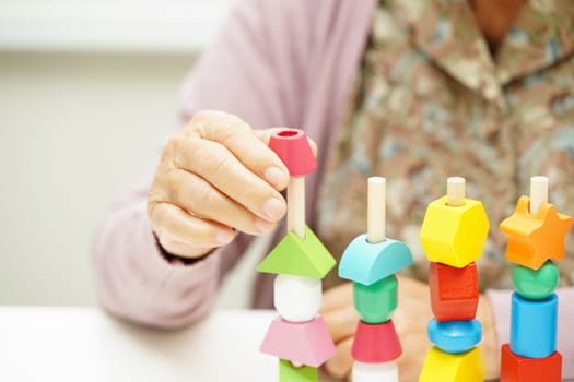 Asian elderly woman playing puzzles game for treatment dementia prevention and Alzheimer disease.