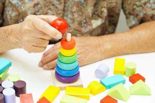 Asian elderly woman playing puzzles game for treatment dementia prevention and Alzheimer disease.