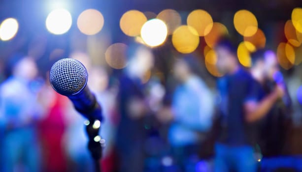 microphone on stage with blurred people and lights in background. AI generated