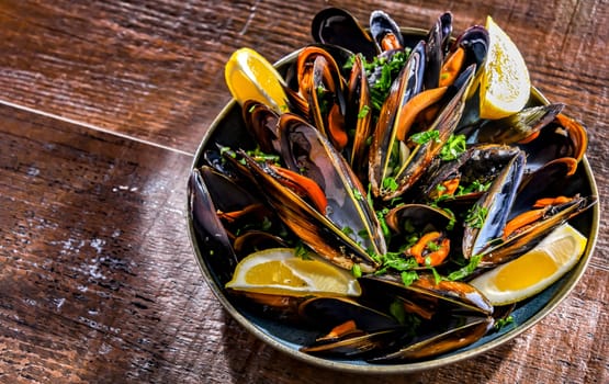 Composition with a plate of steamed mussels served with parsley and lemon