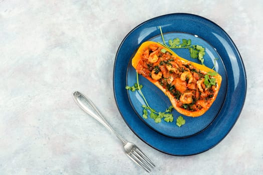 Half a butternut pumpkin stuffed with vegetables and shrimp. Flat lay. Copy space.
