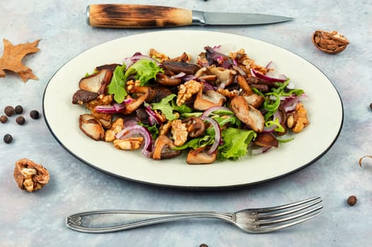 Autumn salad with stewed mushrooms, onions, lettuce and walnuts. Concept healthy food.
