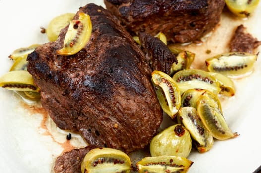 Roasted ostrich steak and mini kiwi on a plate