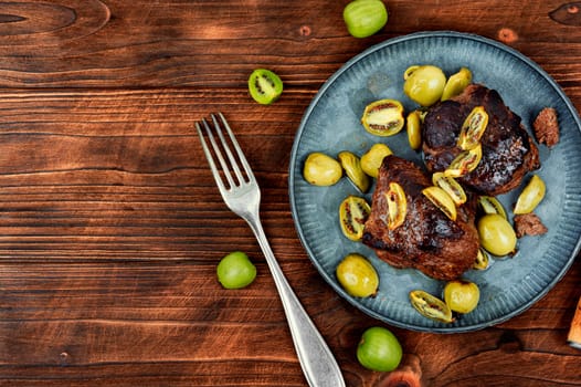 Roasted ostrich steak and mini kiwi on a plate