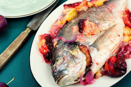 Dorado or sea bream fish baked with plums. Gilthead fishes