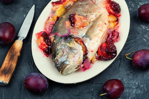 Dorado or sea bream fish baked with plums. Gilthead fishes