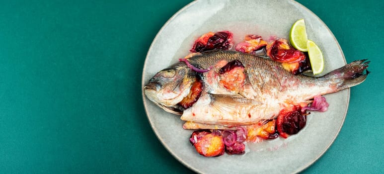 Dorado or sea bream fish baked with plums. Gilthead fishes