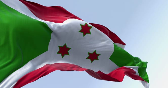 National flag of Burundi waving on a clear day. White diagonal cross dividing into red and green sections, three green stars in the center. 3d illustration render. Fluttering fabric. Selective focus