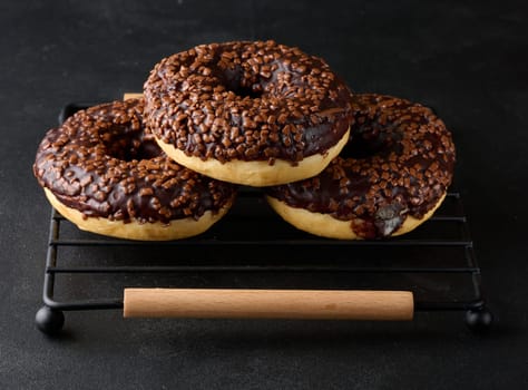 Chocolate donuts sprinkled with crushed nuts on a black table