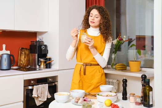 Young woman is going to add sesame seed paste urbech in a bowl with probiotic salad