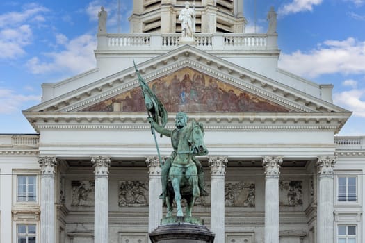 Brussels, Belgium - May 18, 2023: Statue of Godfrey of Bouillon at The Place Royale known as Koningsplein. Neoclassical Church of St. James on Coudenberg in a distance