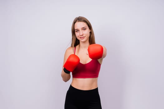 Woman boxer in gloves training on a grey and yellow background