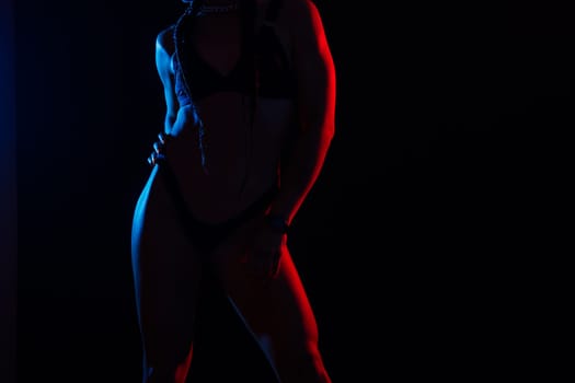 Slim tanned woman's body on dark grey background, studio shot