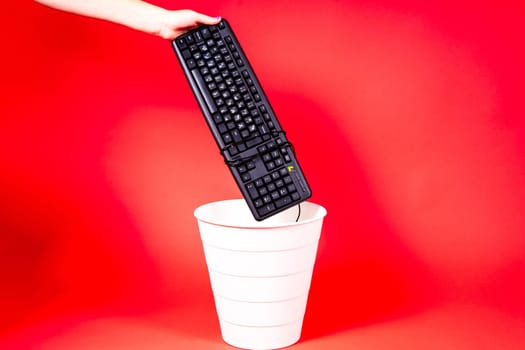 Woman putting a computer keyboard in a e-waste trash bin, recycling concept