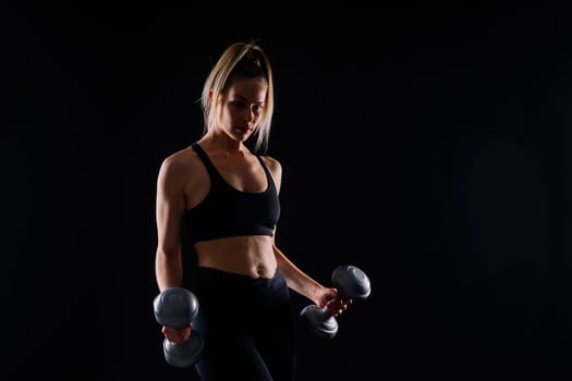 Muscular woman doing exercises with dumbbells on biceps. Photo of strong female isolated on studio