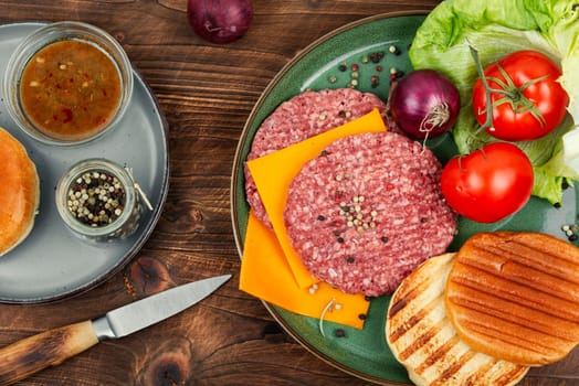 Raw burger cutlets, cheese, vegetables and burger buns for cooking.