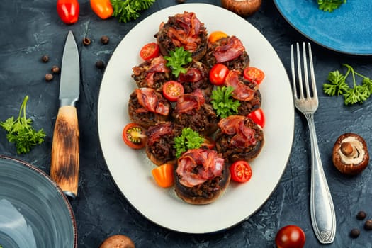 Delicious champignon mushrooms caps stuffed with minced meat and bacon.