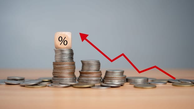 Percent sign on a wooden cube with row of coins in idea for FED consider interest rate hike, inflation concept, red graph arrow, world economics, and inflation control, Money and budget management