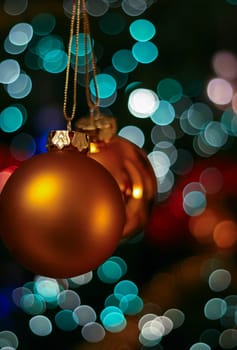 Gold Christmas bauble ball decoration ornament hanging from Christmas tree, bokeh lights background