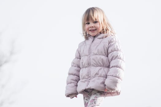 Child portrait of cute trendy little girl in jacket on white background outdoors.