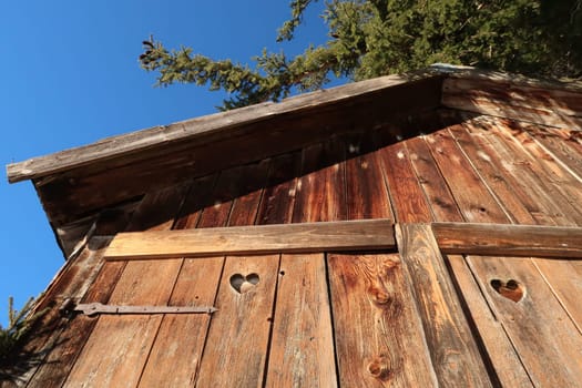 Wooden barn hut shelter shed with heart shaped holes in its doors, Allgau, Germany 2021