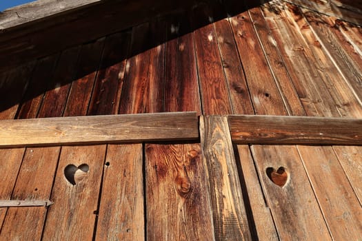 Wooden front of a barn hut shed shelter with heart shaped holes, Allgau, Germany 2021