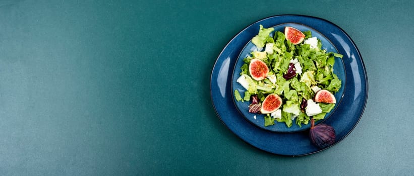 Raw dieting salad with figs, herbs and cheese on old wooden background. Copy space