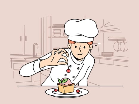 Woman pastry chef prepares dessert cake with fresh berries standing in kitchen of restaurant or bakery. Girl decorates cheesecake with cherry before serving dessert to cafeteria customer.