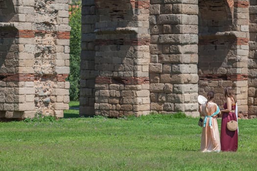 Merida, Spain - June 4th, 2023: Young reenactors women beside Los Milagros Aqueduct. Emerita Ludica Festival 2023, Merida, Spain