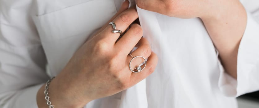 Women Jewelry concept. Woman's hands close up wearing rings and necklace modern accessories elegant lifestyle.