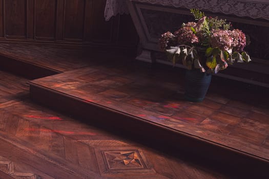 Flowers at the foot of the church altar. Dark atmosphere of contemplation. Photography taken in France