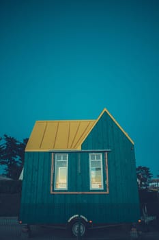 Modern blue tiny house on wheels at the twilight. Copy space for text. Vertical photography taken in France