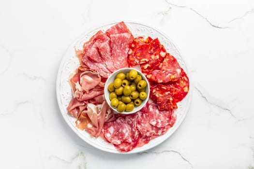 Assortment of Italian and Spanish sliced meat appetizer, prosciutto, salami and ham, with olives