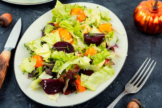 Autumn salad of baked pumpkin, beetroot and greens in a plate on the table. Healthy eating