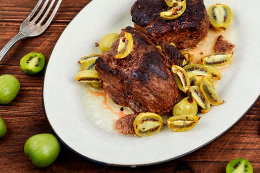 Roasted ostrich steak and mini kiwi on a plate