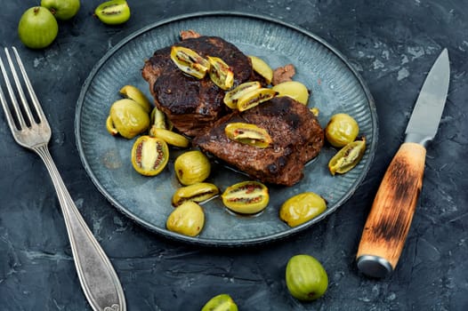 Roasted ostrich steak and mini kiwi on a plate