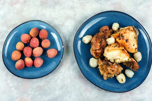 Pieces of grilled or smoked chicken thighs with lychee on a plate. Top view
